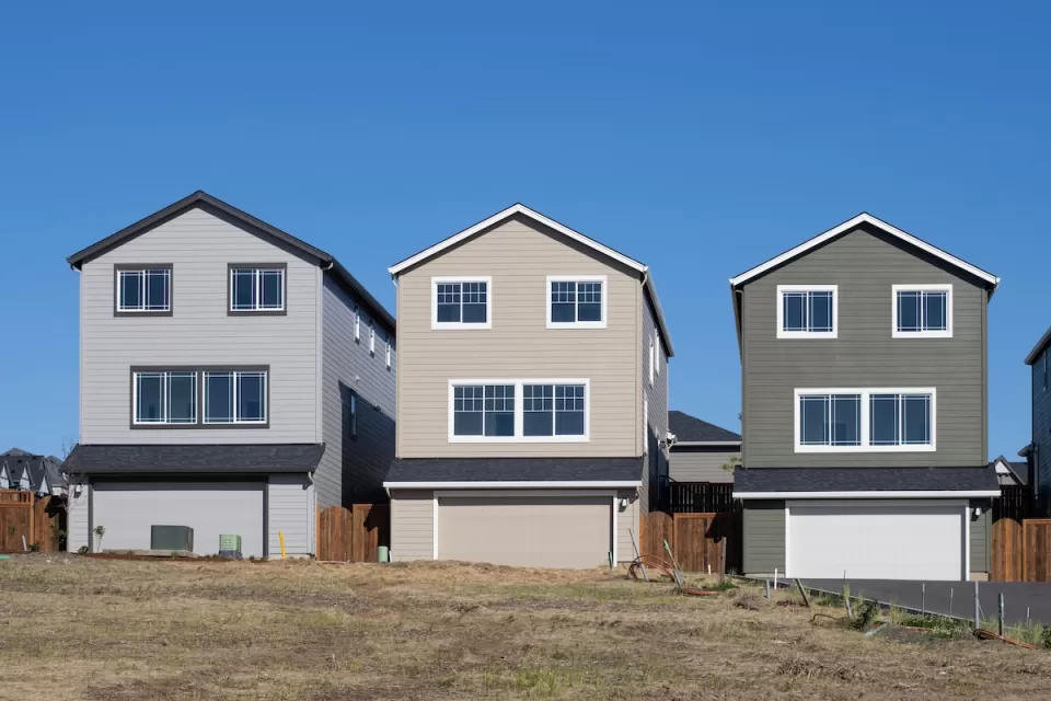 Three new single-family homes in a row on a lot with no trees.